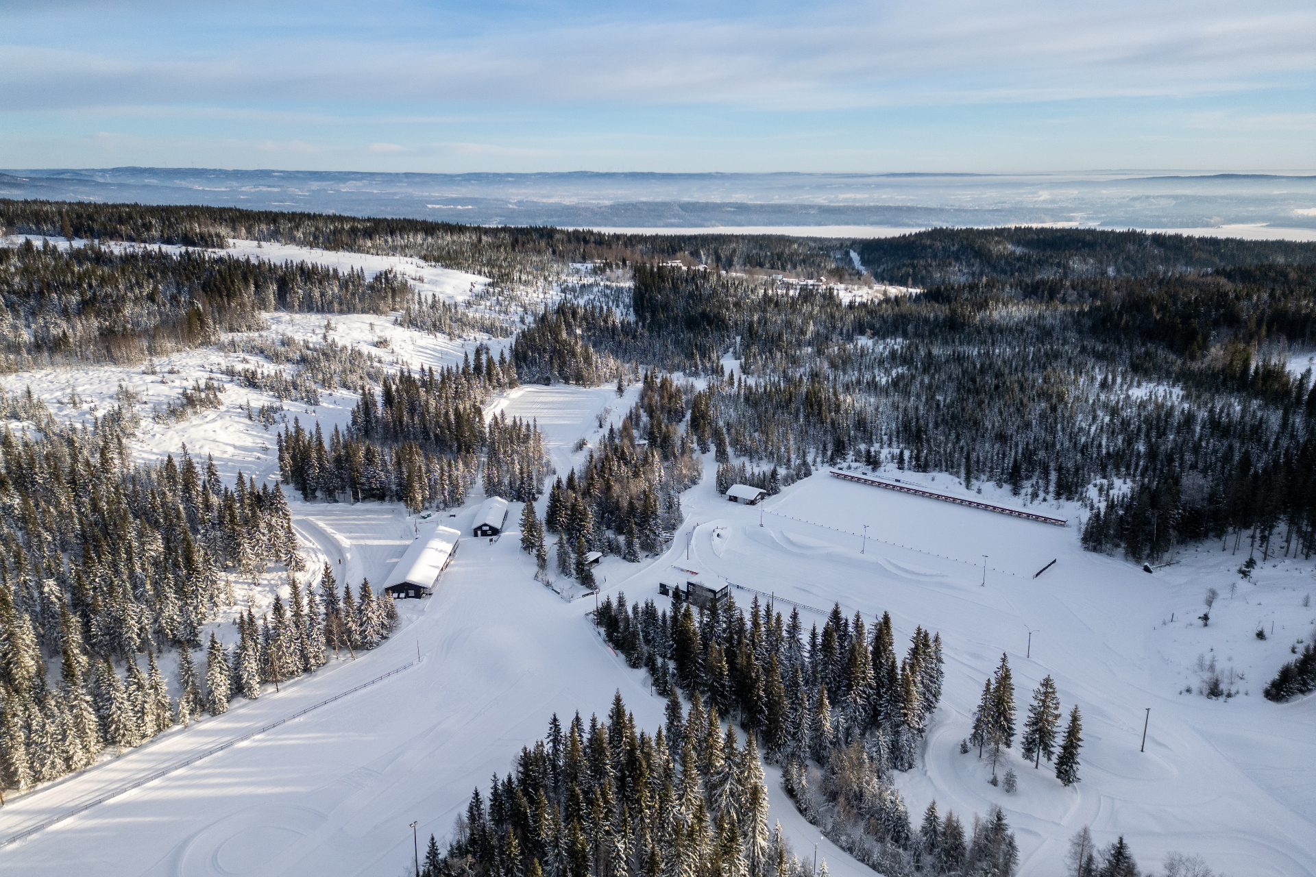 Vinterlandskap med langrennsløyper og skogkledde åser ved Åslia
